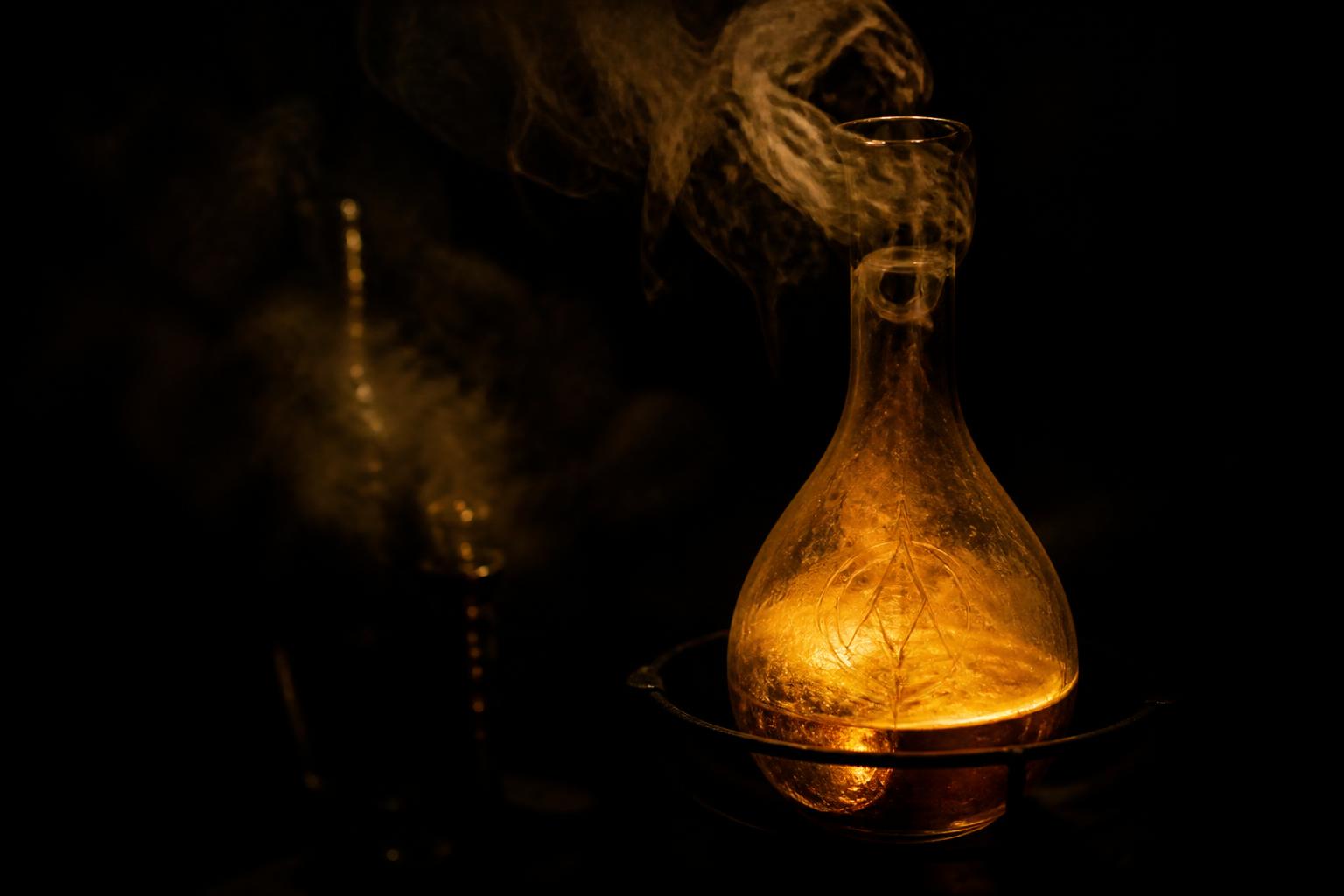 Glaskolben mit goldenem Licht in Dunkelheit