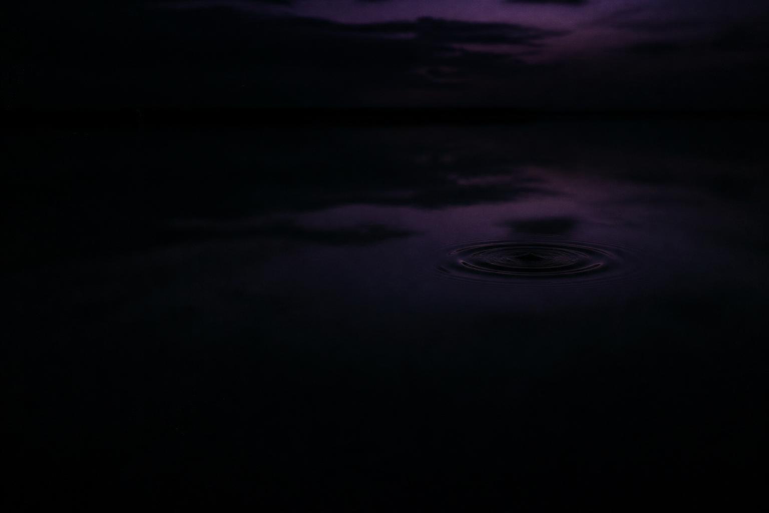 Stilles schwarzes Wasser mit einer Welle